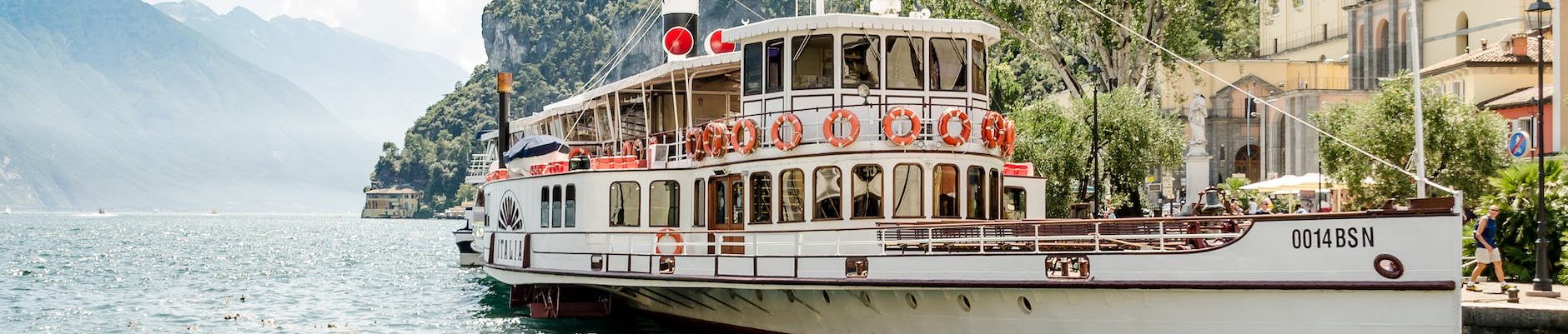 white ship on body of water beside mountain